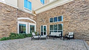 A courtyard with stone walls, outdoor seating, and large windows.