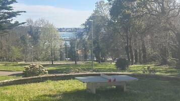 Un parco con un tavolo da ping pong, erba, alberi e una vista in lontananza di edifici.