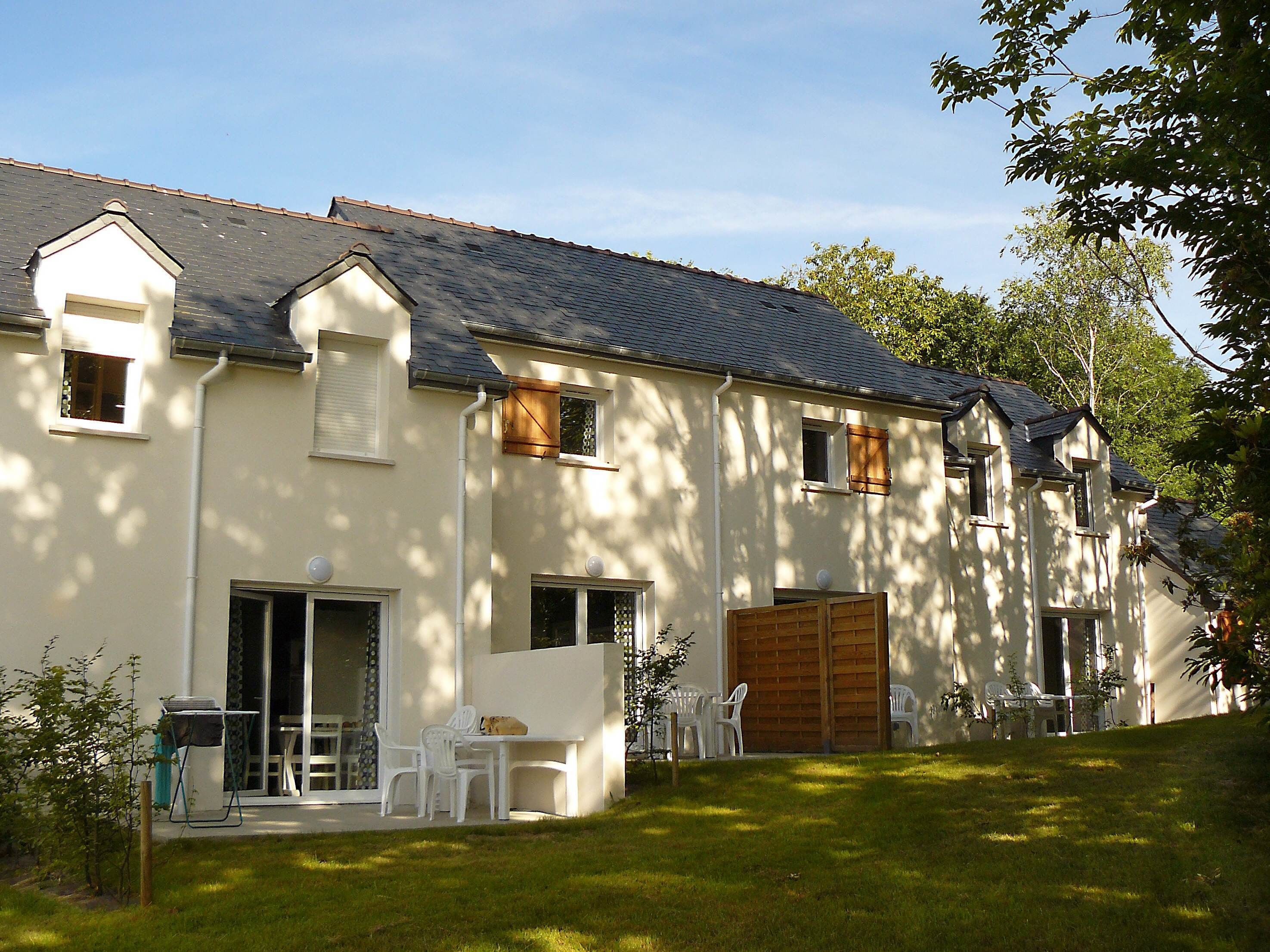 A two-story house with a sloped roof, a garage, and a small patio with outdoor furniture.