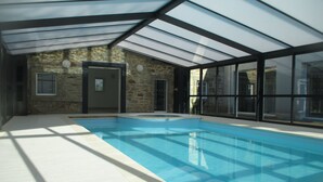 An indoor swimming pool with a glass ceiling, stone walls, and a tiled floor. - Terres de France - Le Domaine de la Baie (Audierne)