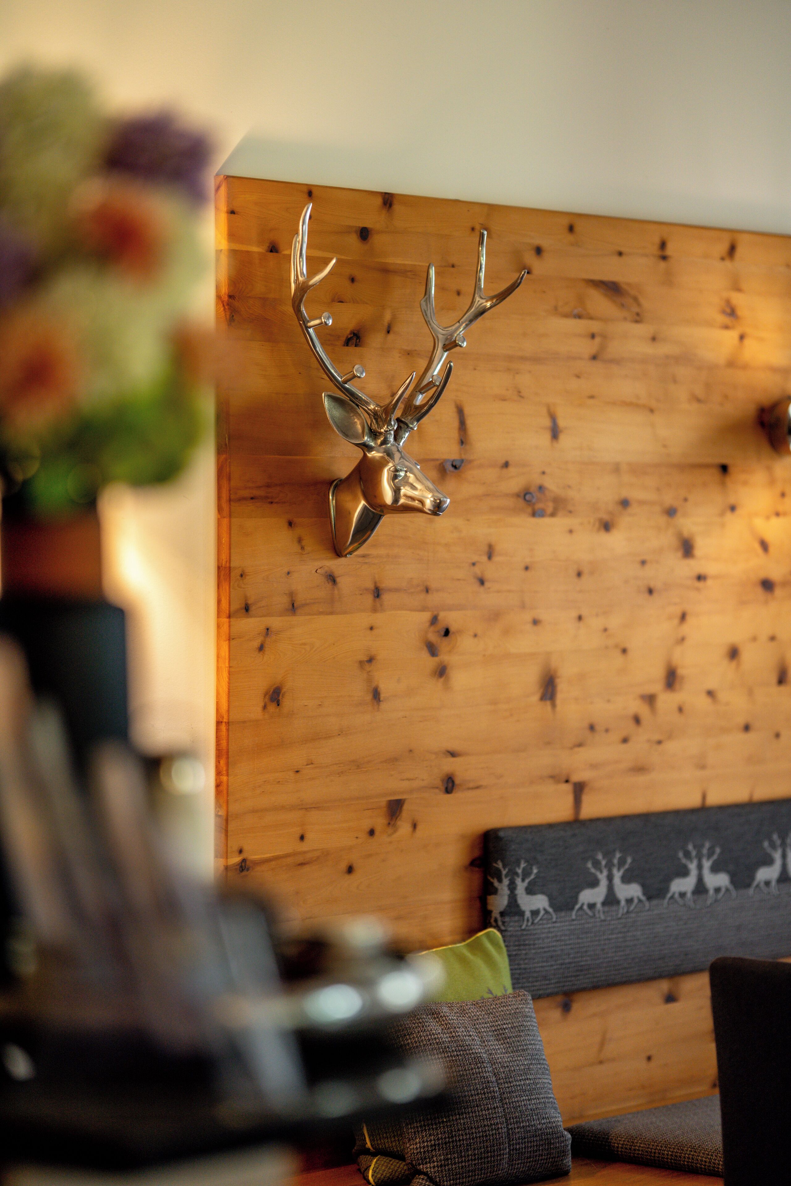 Un mur en bois orné d’une tête de cerf et agrémenté d’un coussin à motifs.