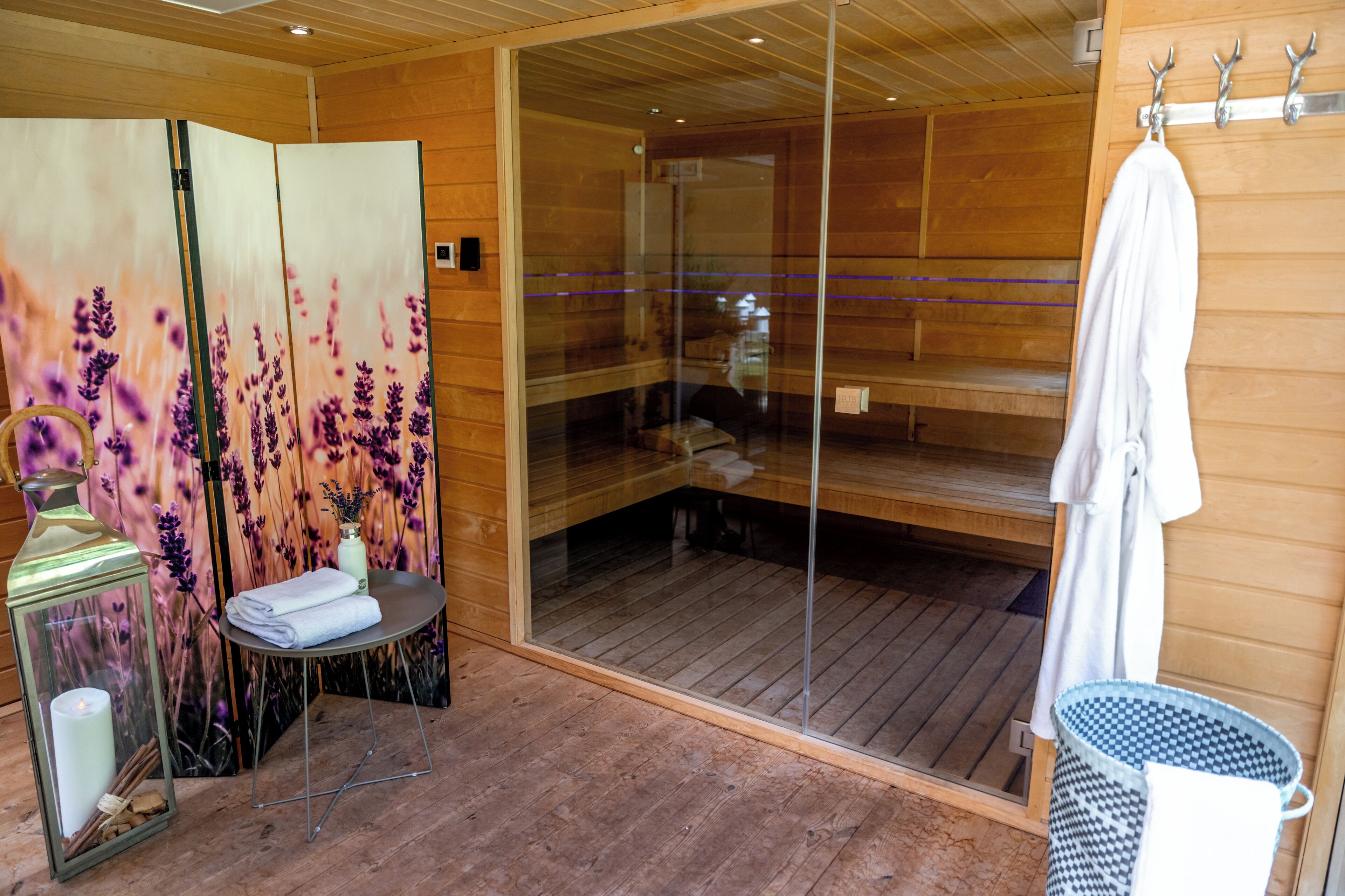 Un sauna avec des murs en bois, une porte en verre et un porte-serviettes.
