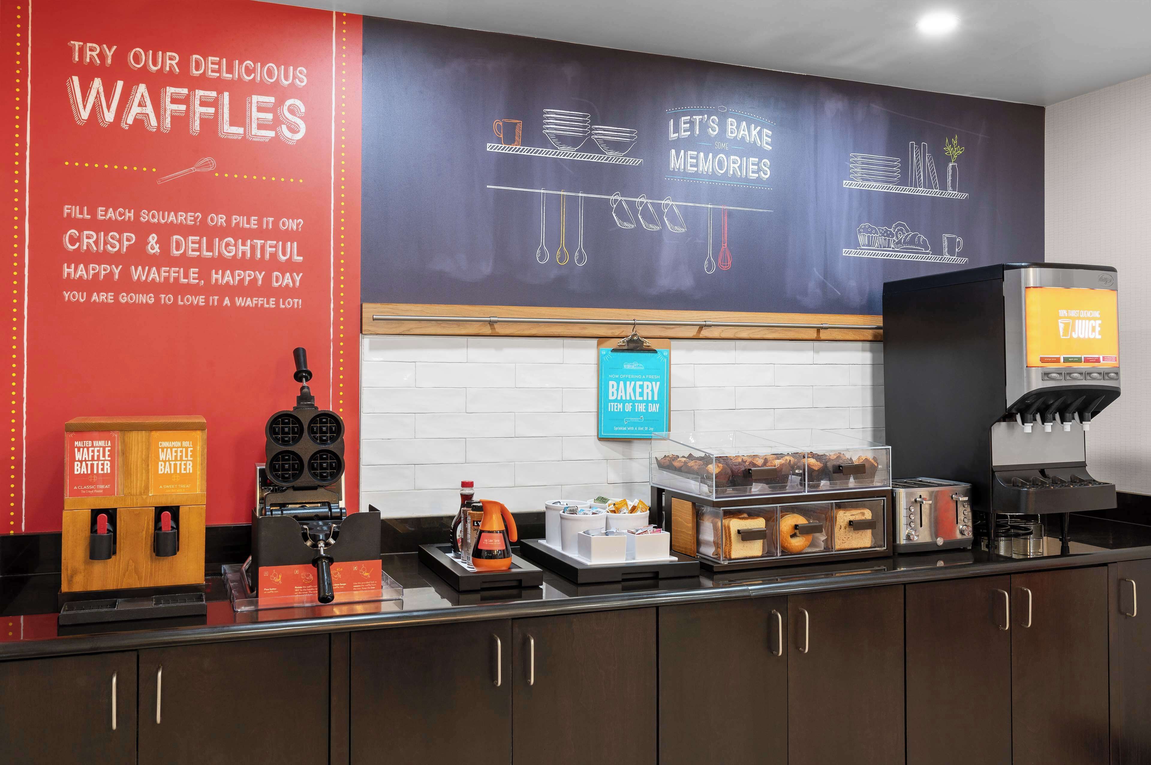 Mostrador de panadería con dispensadores de masa para gofres, una plancha para gofres y una máquina de café.