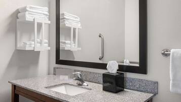 A bathroom with a granite countertop, a white sink, a mirror, and two towel racks.