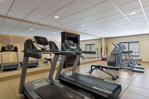 Une salle de sport équipée de tapis de course, de vélos elliptiques et d’autres appareils d’exercice.