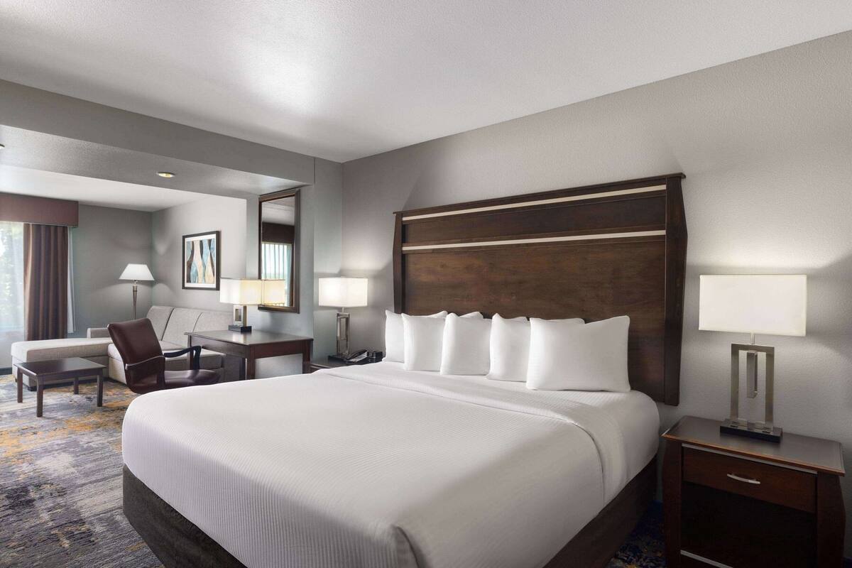 Een hotelkamer met een groot bed, een bureau met stoel, een nachtkastje en een lamp.