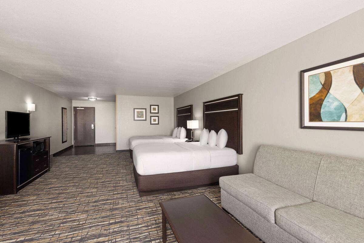 Een hotelkamer met een groot bed, een bank, een televisie en een vloerbedekking.