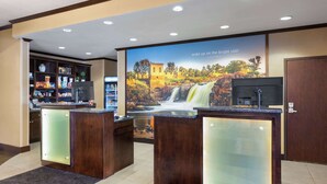 A reception area with a large poster of Sioux Falls, a reception desk, a glass display case, and a shelf with various items.