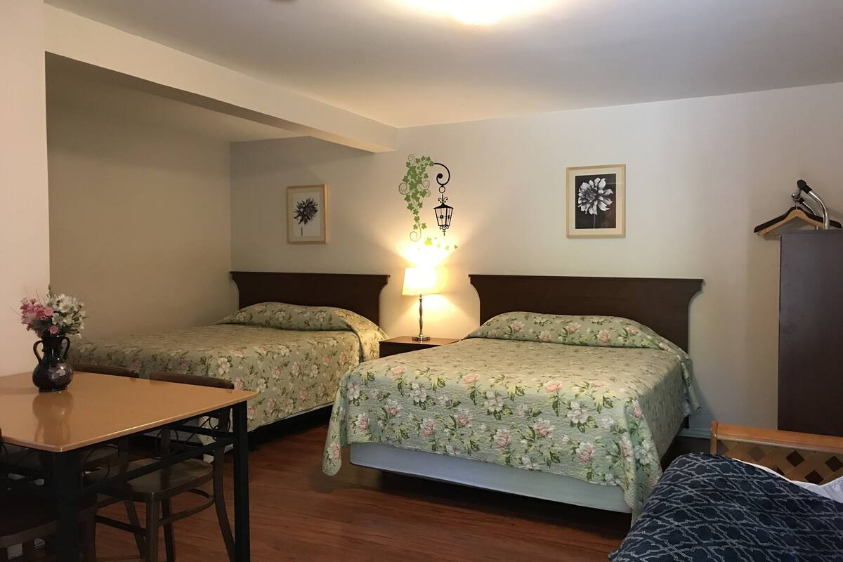 A hotel room with two single beds, a wooden table, a desk, a lamp, and a wardrobe.