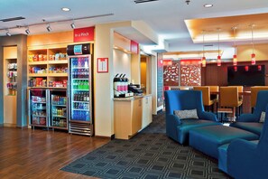 A hotel lobby with seating areas, a refreshment bar, and vending machines. - TownePlace Suites by Marriott Dodge City (Dodge City)