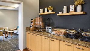 Una cocina moderna con encimeras de granito, armarios de madera y varios electrodomésticos, incluyendo un fabricante de gofres y un tostador.