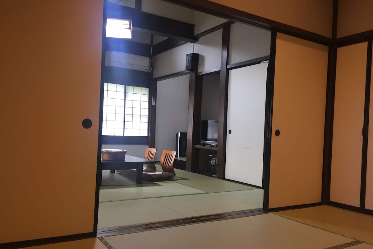 A traditional Japanese room with tatami flooring, a sliding door, and a low table with cushions.