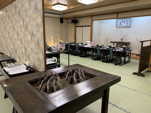 Ein traditioneller japanischer Raum mit Tatami-Bodenbelag, einem Holztisch mit Fisch und einer Teeausstattung.