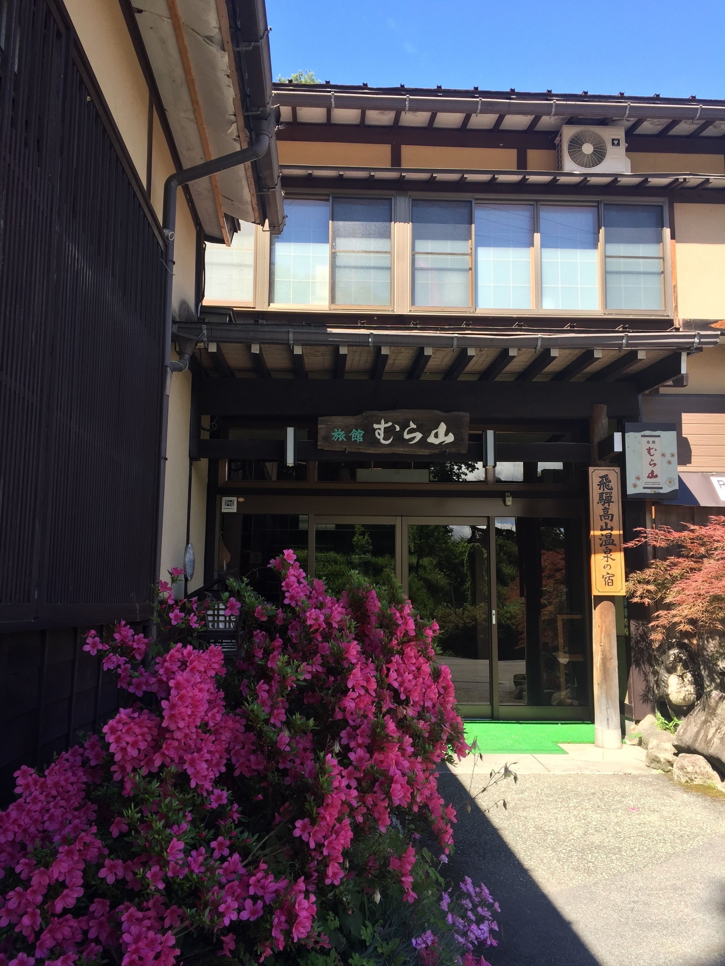 Un edificio japonés tradicional con entrada de madera y un letrero.