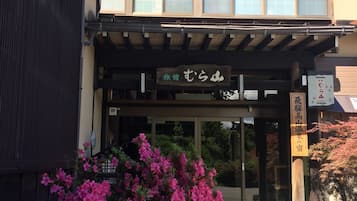 Un edificio japonés tradicional con entrada de madera y un letrero.