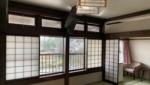 Ett traditionellt japanskt rum med tatamimattor på golvet, skjutbara shojidörrar och ett träpanelat tak.