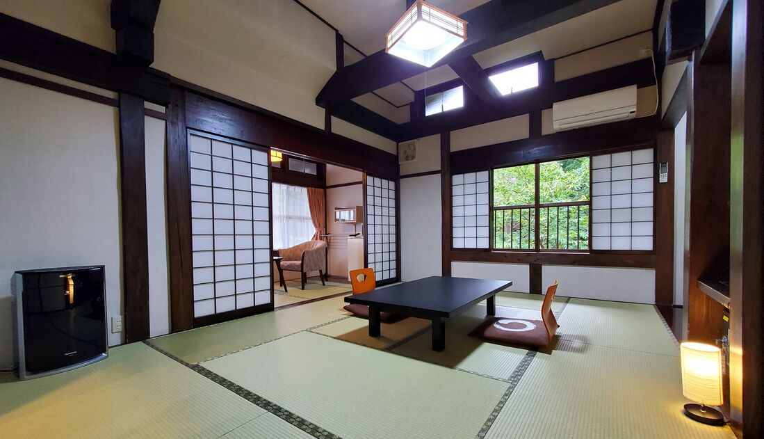 A traditional Japanese room with tatami flooring, a low table, a chair, and sliding doors.