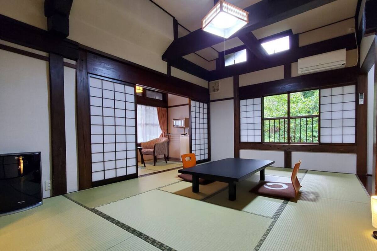 A traditional Japanese room with tatami flooring, a low table, a chair, and sliding doors.