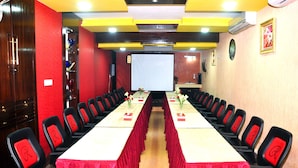 A conference room with a long table, chairs, a projector screen, and a clock on the wall. - Hotel Rose Garden (Dhaka)