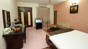 A hotel room with a bed, a desk with a computer, a television, and a sofa. - Hotel Rose Garden (Dhaka)