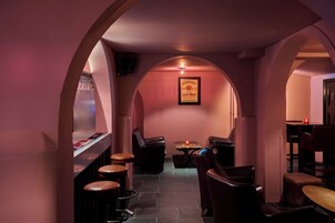 Un coin bar à la lumière tamisée, avec des sièges en cuir et un panneau encadré accroché au mur.