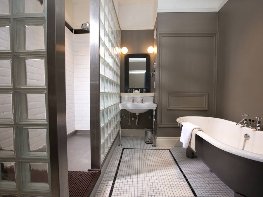 Un bagno con porta in vetro, lavandino, specchio e vasca da bagno.