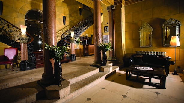 Un vaste hall d’entrée avec un escalier, des colonnes, un canapé et une table basse.