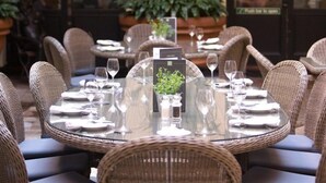 Un espace extérieur aménagé pour les repas, avec des chaises et des tables en osier, prêts pour un repas.