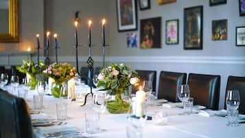 Una mesa de comedor decorada con velas, copas y un jarrón con flores.
