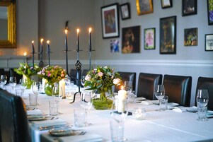 Una mesa de comedor decorada con velas, copas y un jarrón con flores.