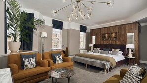 Une chambre d’hôtel avec un grand lit, un canapé, une table basse et une plante en pot.