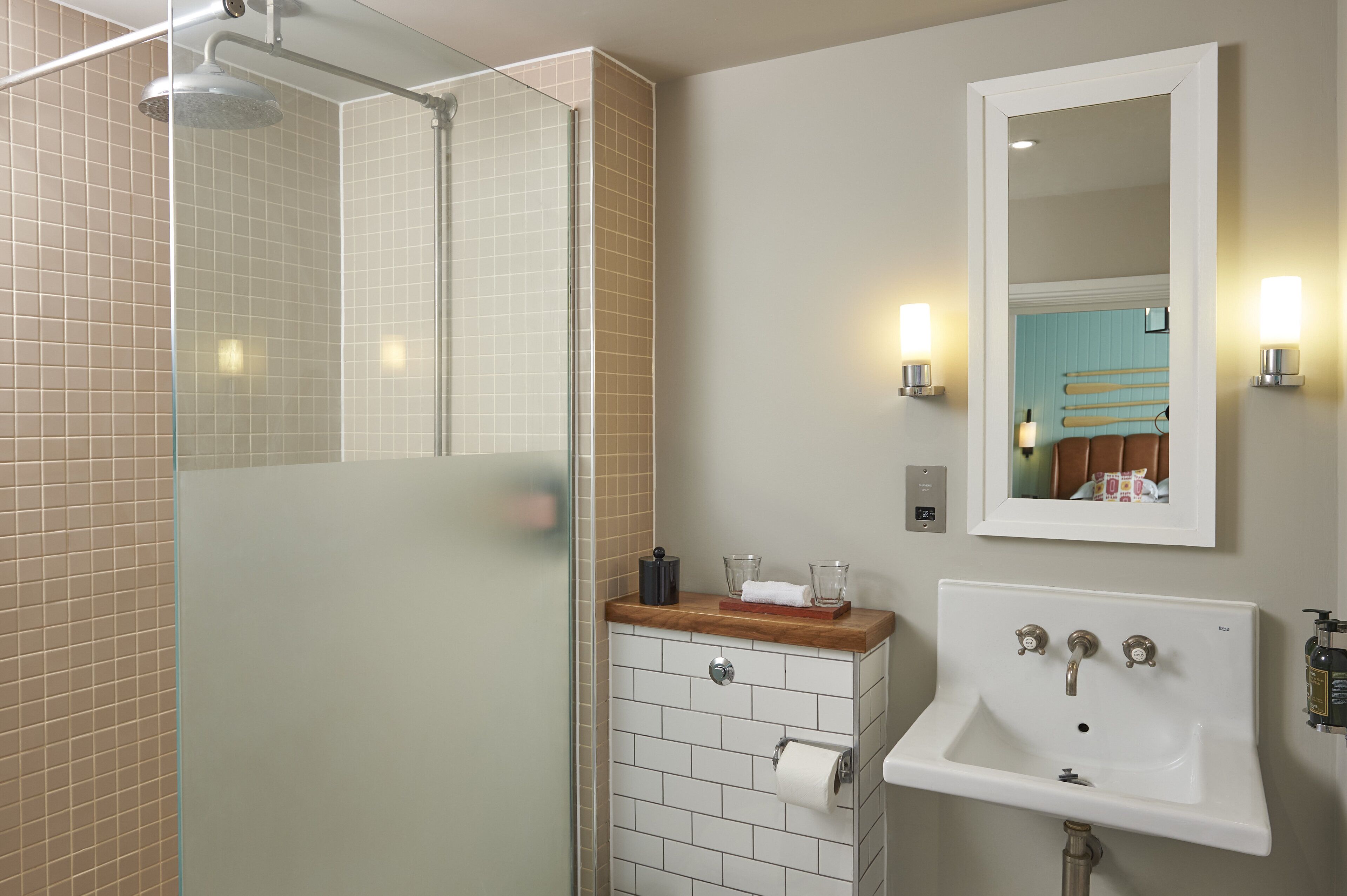 Un baño con cabina de ducha de vidrio, un lavamanos con encimera de madera y un espejo con luces empotradas.
