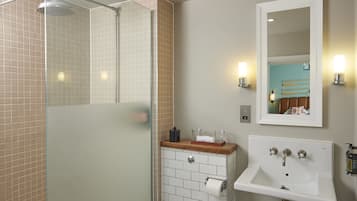 Un baño con cabina de ducha de vidrio, un lavamanos con encimera de madera y un espejo con luces empotradas.