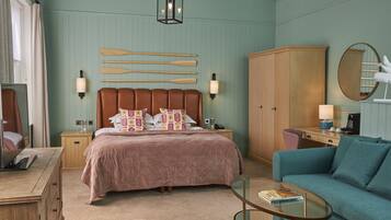 A bedroom with a bed, bedside tables, a wardrobe, a sofa, a glass coffee table, and a mirror.