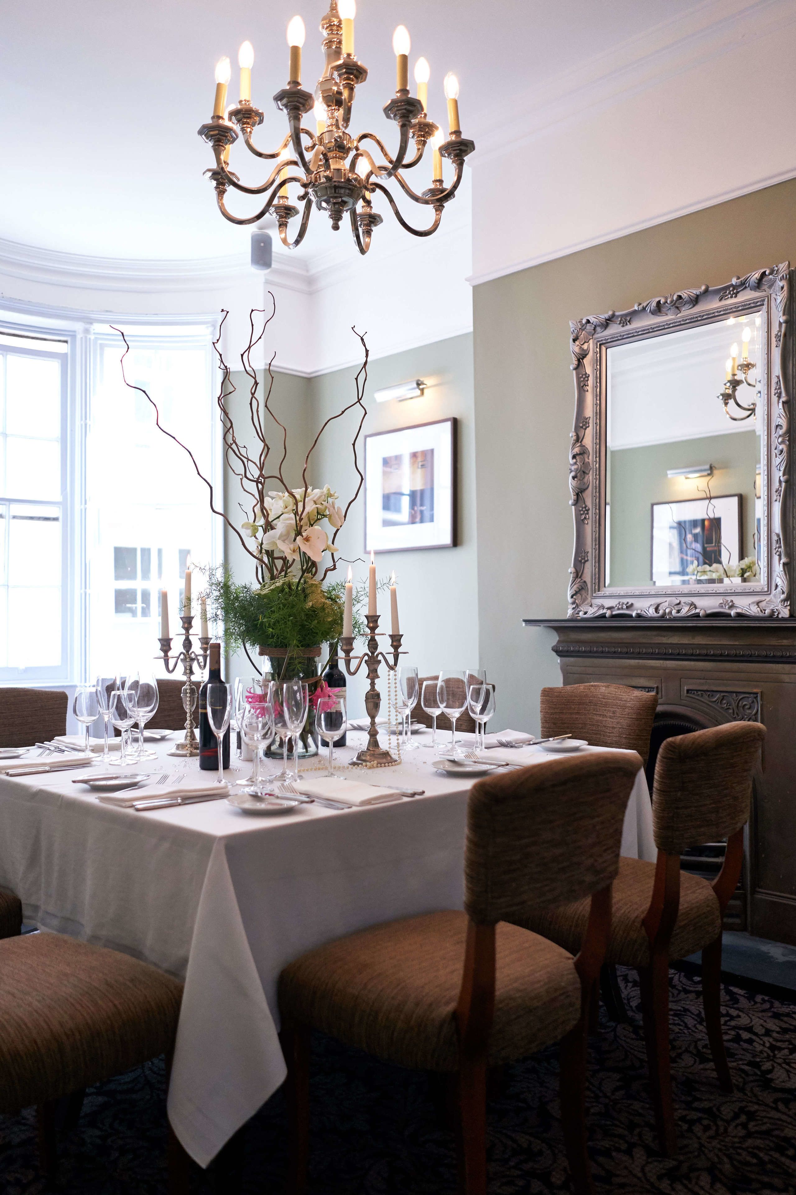Ein Esszimmer mit einer Chandelier, einem großen Spiegel und einem Tisch, gedeckt für sechs Personen.