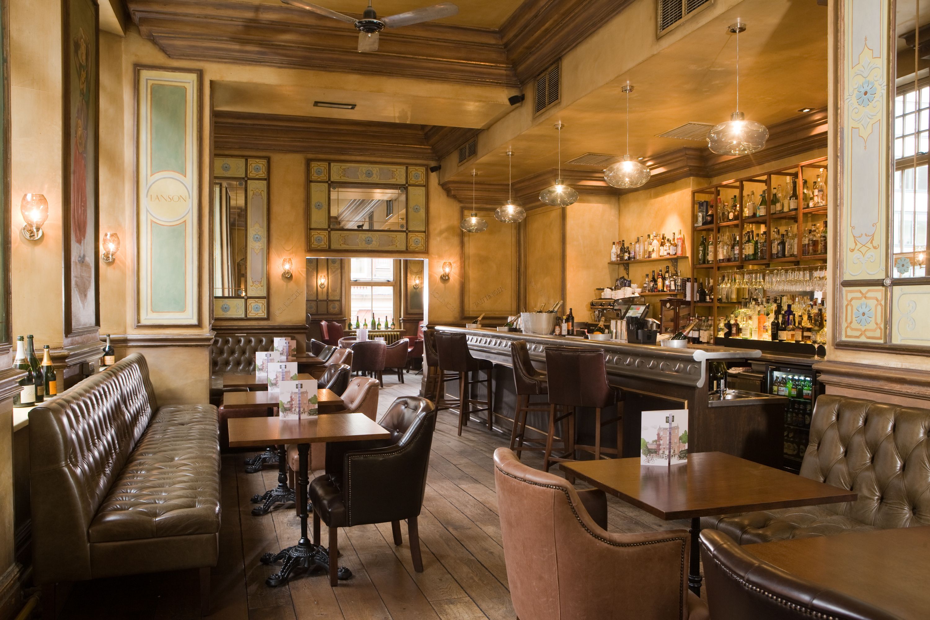 A bar area with leather seating, a piano, and a well-stocked liquor shelf.