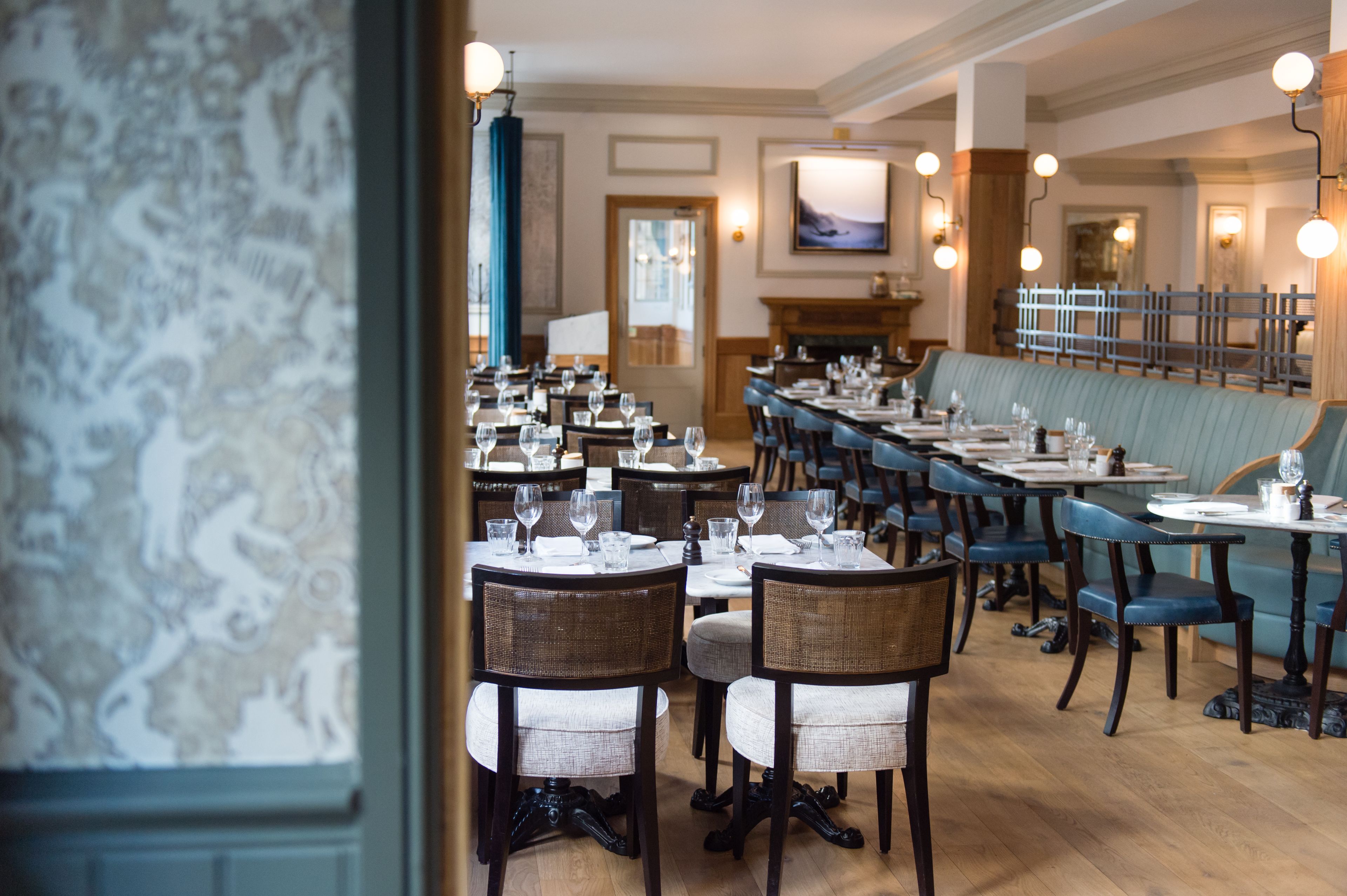 Ein Restaurant mit einem langen Esstisch, Stühlen und einer blauen Sitzbank.
