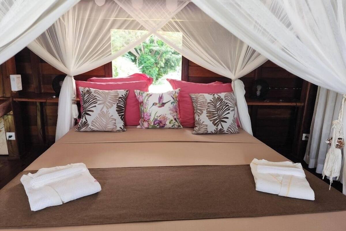 A bed with a canopy, pillows, and towels.