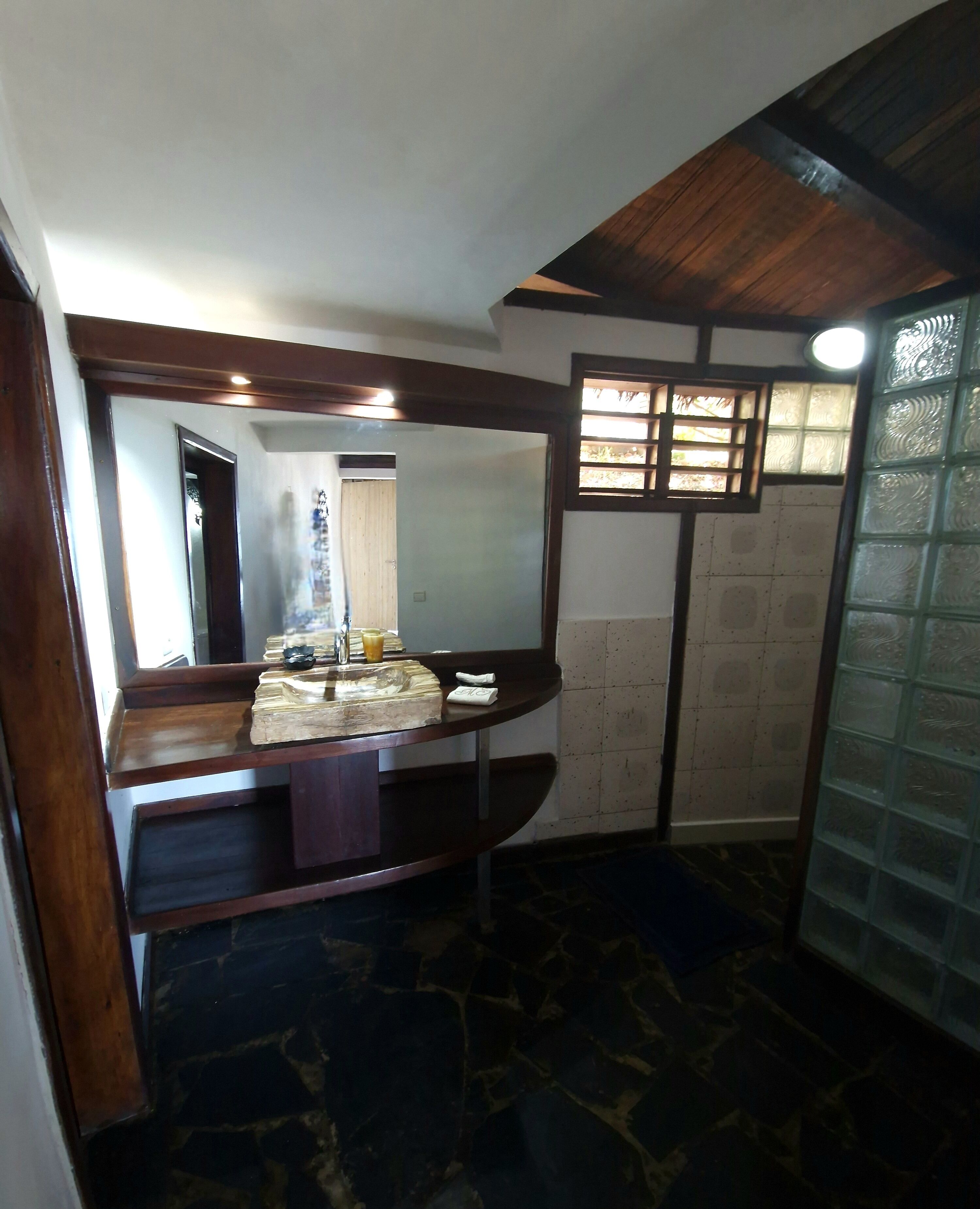 A bathroom with a large mirror, a sink, and a tiled floor.