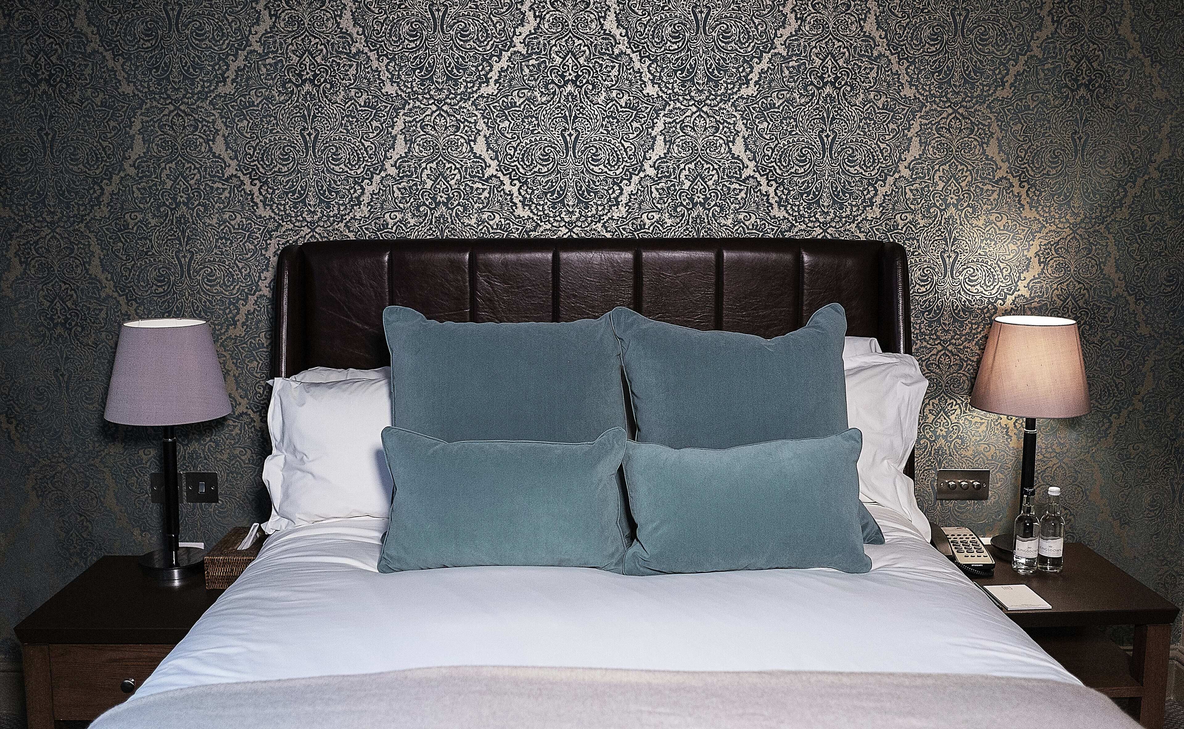 A bed with a dark headboard, two pillows, and two bedside lamps.