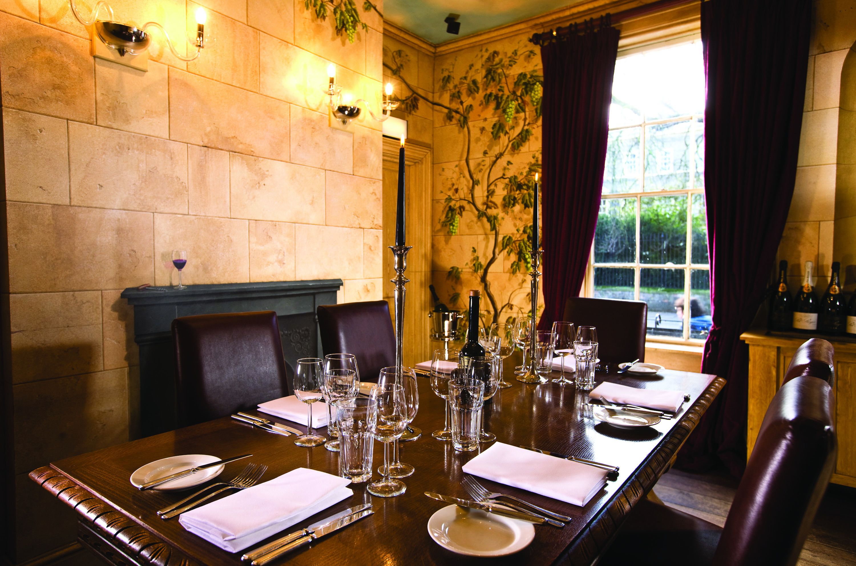A dining table set for a meal with wine glasses, plates, and cutlery.