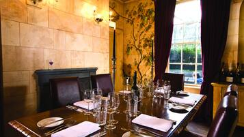 A dining table set for a meal with wine glasses, plates, and cutlery.