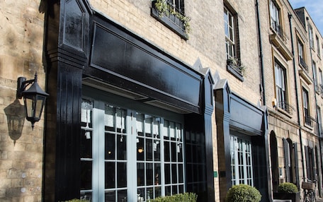 A brick building with large windows and outdoor seating.