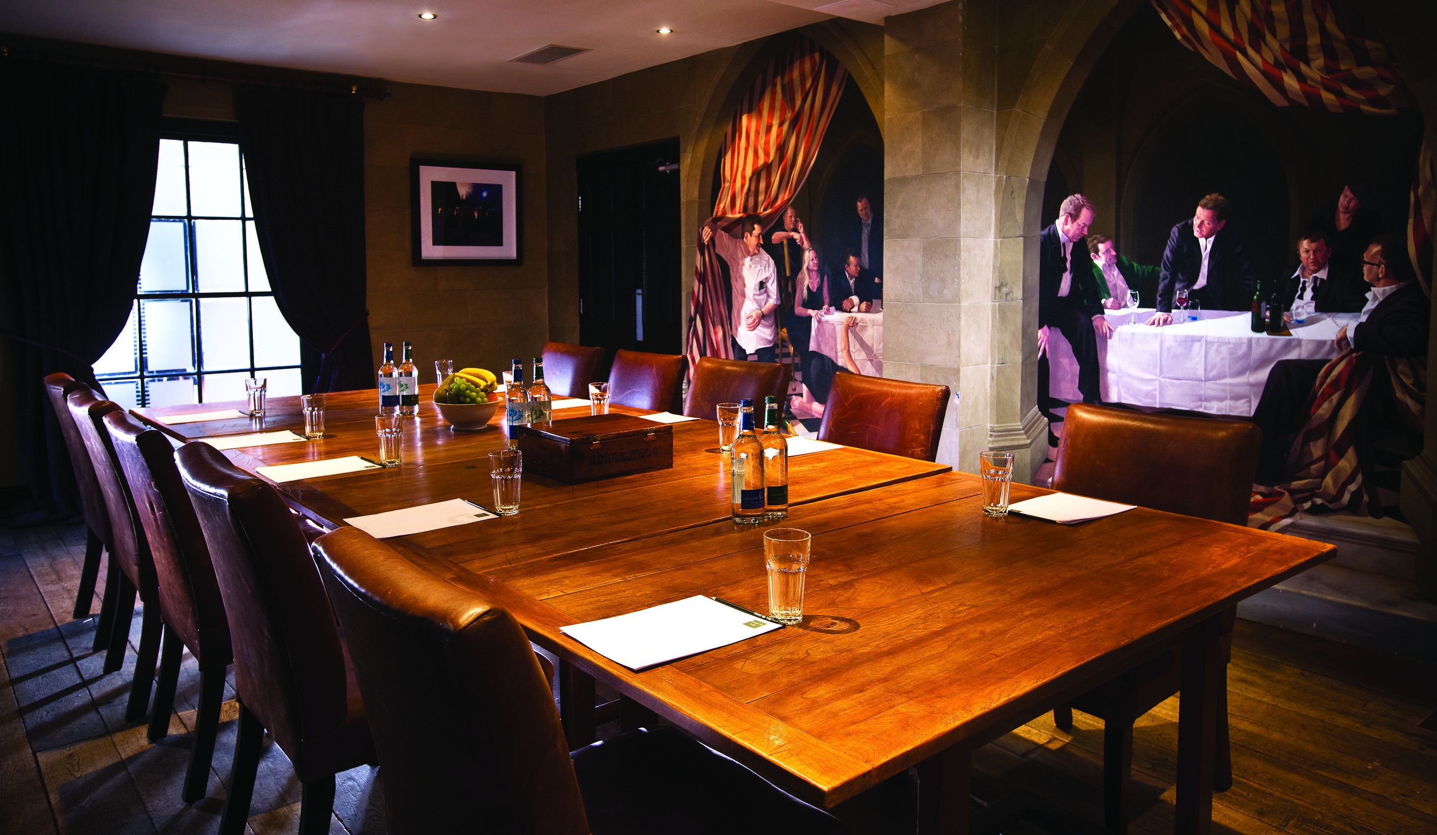 A conference room with a long wooden table, chairs, and a small bowl of fruit.