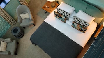 Ein ordentlich eingerichtetes Schlafzimmer mit einem Bett, zwei Stühlen, einem Nachttisch mit Lampe und einem kleinen runden Tisch.