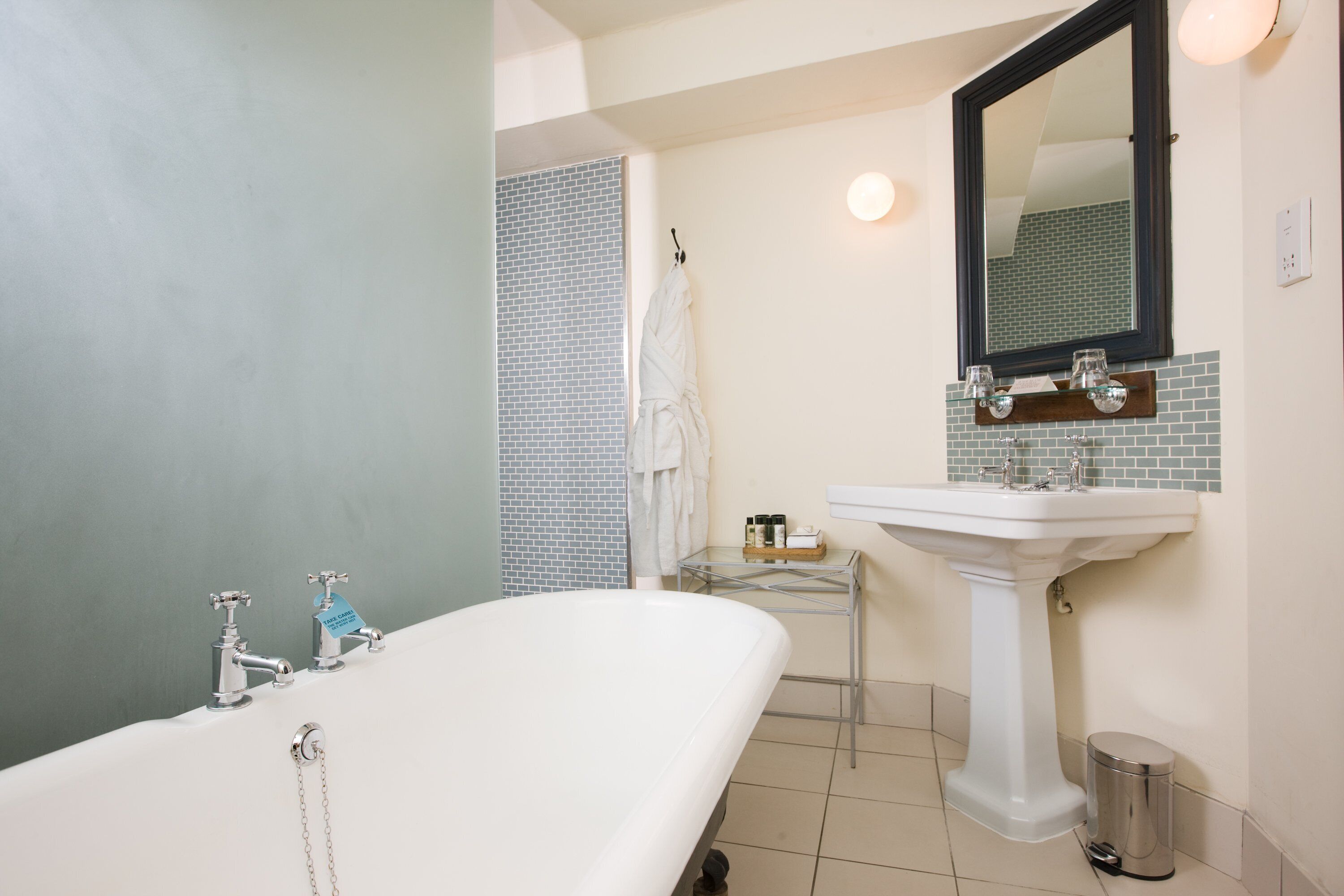 A bathroom with a bathtub, a sink, a mirror, and a tiled shower area.