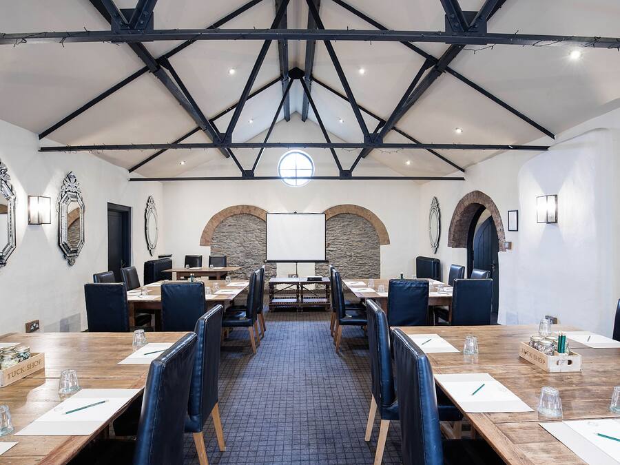 A conference room with a high ceiling, wooden tables, and blue chairs.