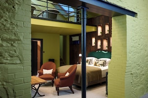 Una habitación con una cama, dos sillones, una mesa y vistas a un balcón.
