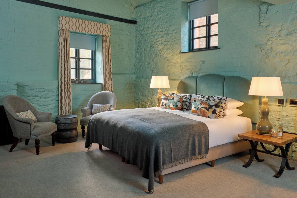 Ein Schlafzimmer mit einem Bett, zwei Stühlen, einem runden Tisch und einer Lampe.