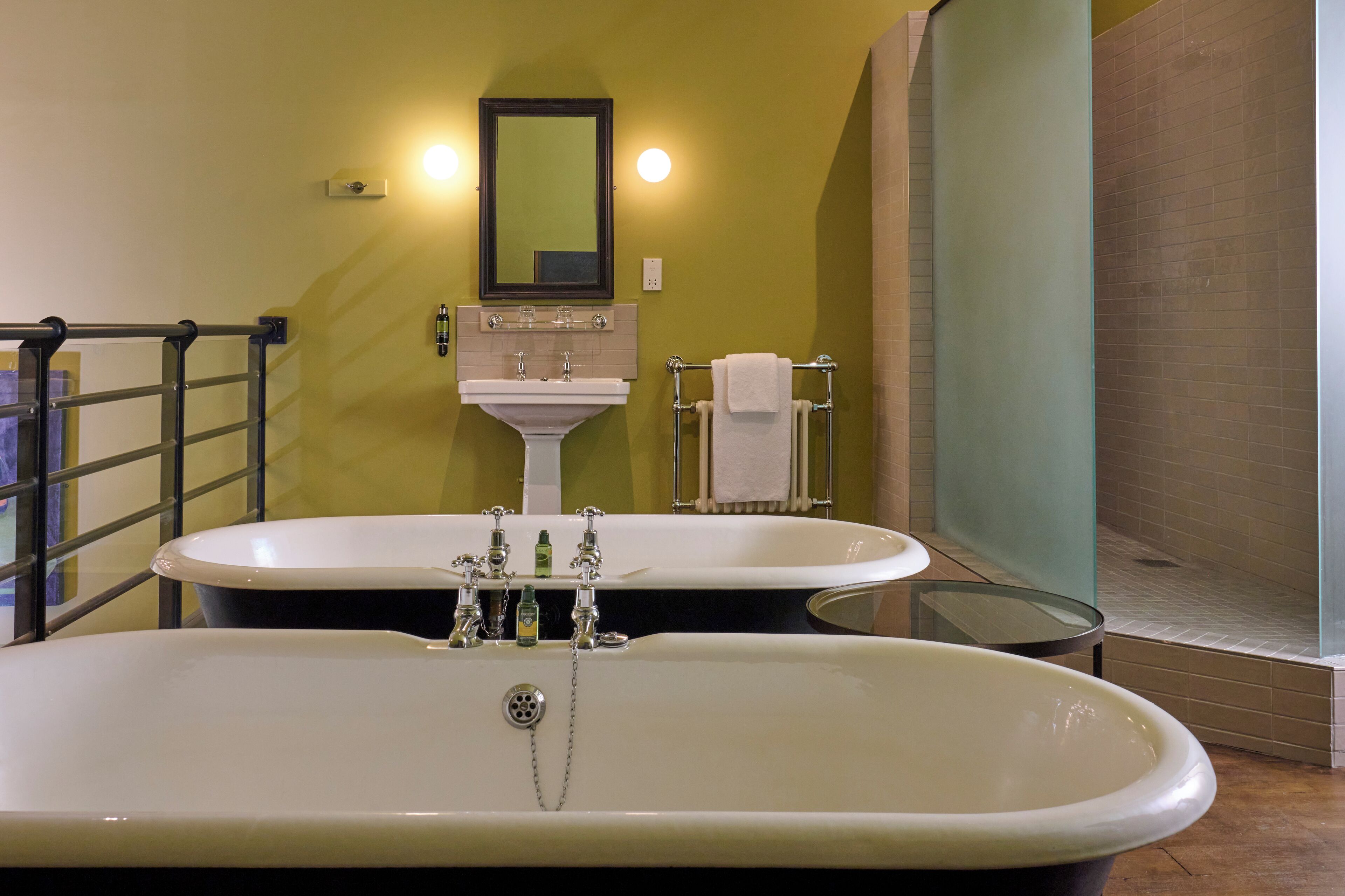 A bathroom with a large bathtub, a sink, and a glass shower enclosure.